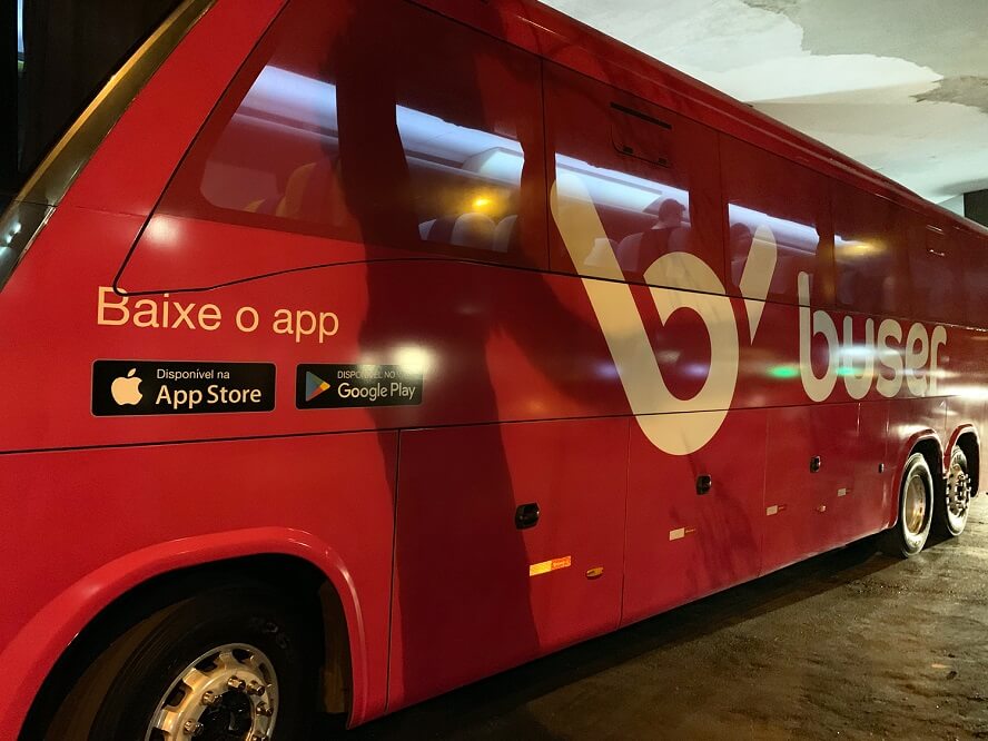 Ônibus vermelho plotado com a marca da Buser